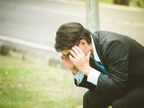 Business man sitting in outdoors park and stressed because of business work failure