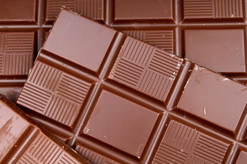 Chocolate bars as background. Milk and dark shiny chocolate texture. Stack chocolates pattern. Stunning beautiful cacao brown dessert sweets.