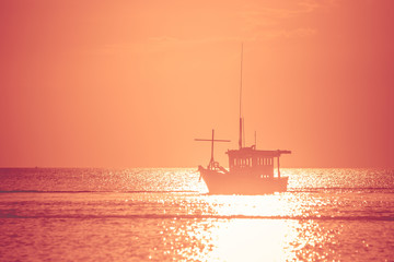 Beautiful seascape view of fishing boat floating on the sea with sunset light in the background. (Selective focus)