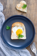 Egg in a heart-shaped bread with parsley, romantic breakfast.