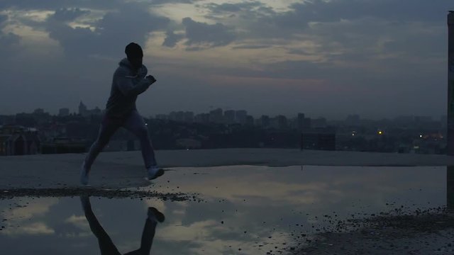 Male traceur running on roof learning new tricks and movements, street parkour