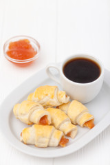 Freshly baked croissant, jam, cup of black coffee on white wooden background. Homemade cookie. Fresh pastries for breakfast. Delicious dessert. Closeup photography. Horizontal banner