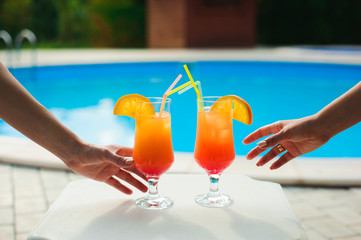 Bikini women in pool relaxing with juice, young beautiful sexy girls resting in vacation on summer...