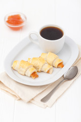 Freshly baked croissant, jam, cup of black coffee on white wooden background. Homemade cookie. Fresh pastries for breakfast. Delicious dessert. Closeup photography. Horizontal banner