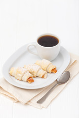 Freshly baked croissant, jam, cup of black coffee on white wooden background. Homemade cookie. Fresh pastries for breakfast. Delicious dessert. Closeup photography. Horizontal banner