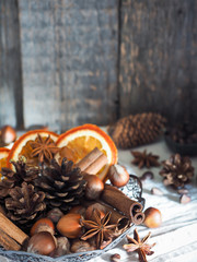 Winter ingredients nuts, cones, oranges, cinnamon star anise in a bowl. Rustic style