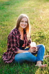 Girl with a glass of juice on a green meadow