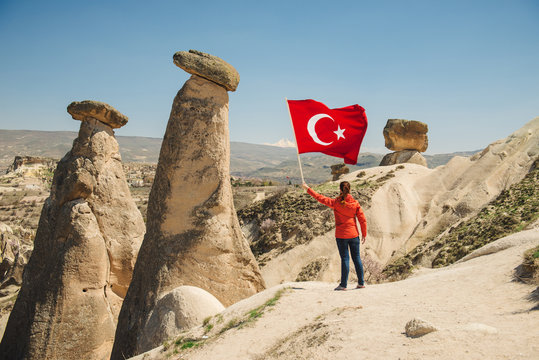 Young traveler with Turkish flag in Cappadocia desert landscape