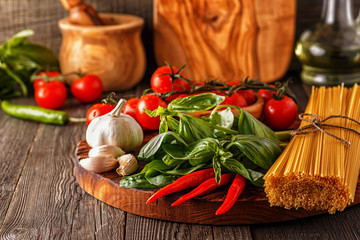 Products for cooking - pasta, tomatoes, garlic, pepper, and basil.
