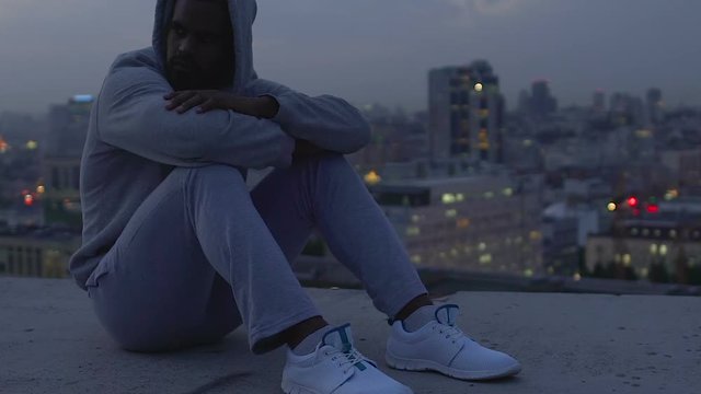 Offended and frustrated guy thinking about meaning of life, sitting on roof edge