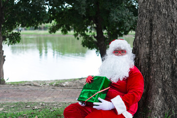 Santa claus with gift box sit under tree,Thailand people,Sent happiness for children,Merry christmas,Welcome to winter