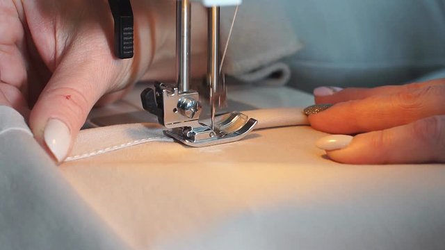Slow motion of a professional sewing machine stitching with white thread an Italian haute couture fabric, The seamstress sews a high fashion outfit. concept of industry, tradition, fashion.