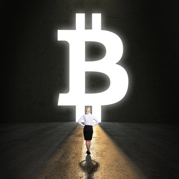 Geschäftsfrau steht vor Portal in Form eines Bitcoin Symbols