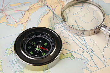 Fototapeta na wymiar Compass and magnifying glass on map