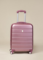 Pink trolley suitcase isolated on beige background
