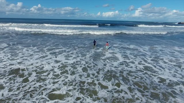 two surfers going into surf aerial footage