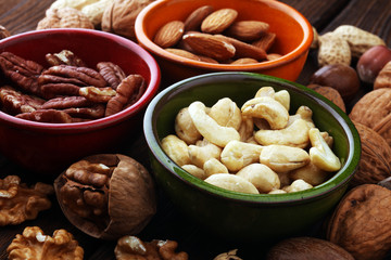 bowls with mixed nuts on wooden background. Healthy food and snack. Walnut, pecan, almonds, hazelnuts and cashews.