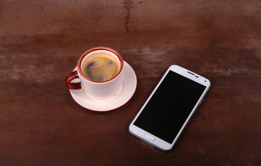 Fototapeta na wymiar Coffee cup and smartphone on wooden table. View from above