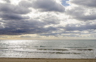 View from sand beach of heavy mediteranean sea with waves and cloudy storm sky