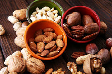 bowls with mixed nuts on wooden background. Healthy food and snack. Walnut, pecan, almonds, hazelnuts and cashews.