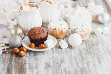 Cups with cacao and marshmallow, cupcakes and different Christmas decorations, wooden background