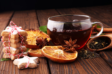 Christmas hot tea with spices and cookies on wooden table.