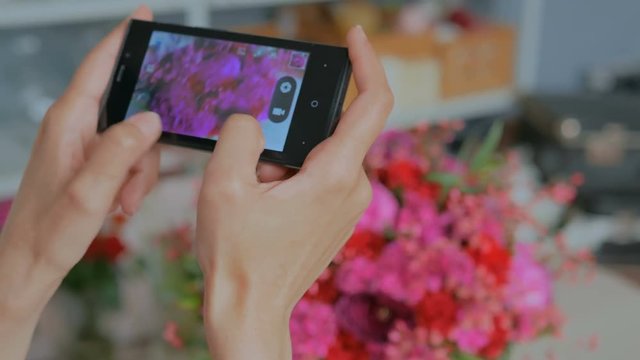 Professional floral artist, florist taking photo of her beautiful wedding bouquet with smartphone. Close up shot of woman's hands with mobile. Photography, technology and social media concept