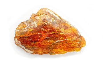 Technology of processing amber. A beautiful large piece of amber during polishing on a white background. Amber with polishing paste and traces of chalk. A natural mineral for jewelry. A sunstone. 