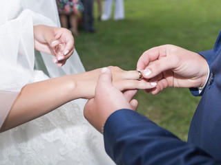 Obraz na płótnie Canvas Groom puts in ring on bride's finger during wedding ceremony