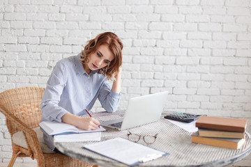 Woman freelancer female hands with pen writing on notebook at home or office