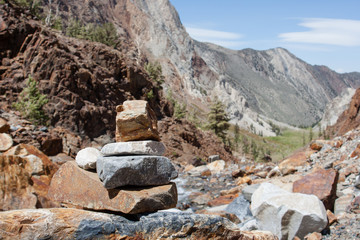 Naklejka premium Rocks stacked up on a hiking trail in California with mountains in the background. 