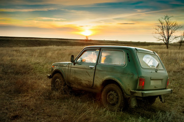Obraz premium dirty SUV in the evening in the field