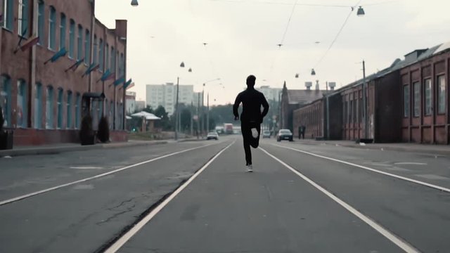 Man running along an old city district street. Back view. On the way to success and reaching goals. Contrast shot.