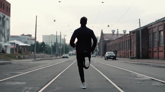 Man running in the middle of the street. Background shot. Slow motion. Abstract concept of individual success and fame.