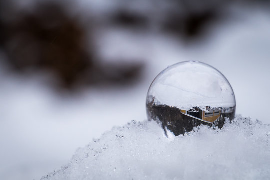 A crystal ball on a snow pile is reflecting surrounding