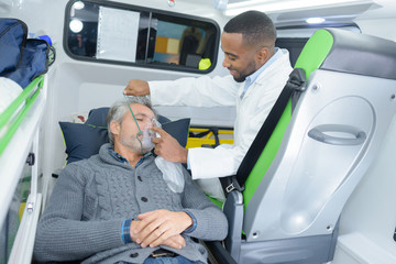 paramedic puts oxygen mask on patient in ambulance © auremar