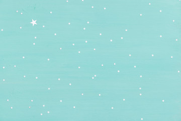 turquoise wooden background with small shiny silver stars. Holidays, Christmas or any other celebration.