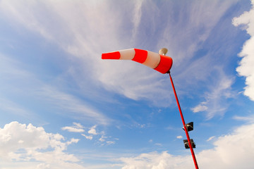 Striped red and white windsock against blue sky