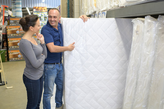 positive couple choosing mattress inside boutique
