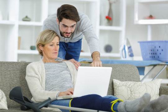 Man looking at laptop over shoulder of injured woman