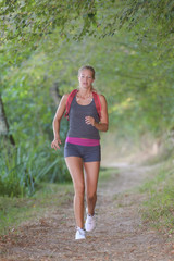 young female endurance runner jogging in the forest