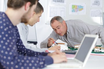 group of students with blueprint meeting indoors