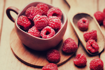 Raspberries in a cup and wooden scoop 