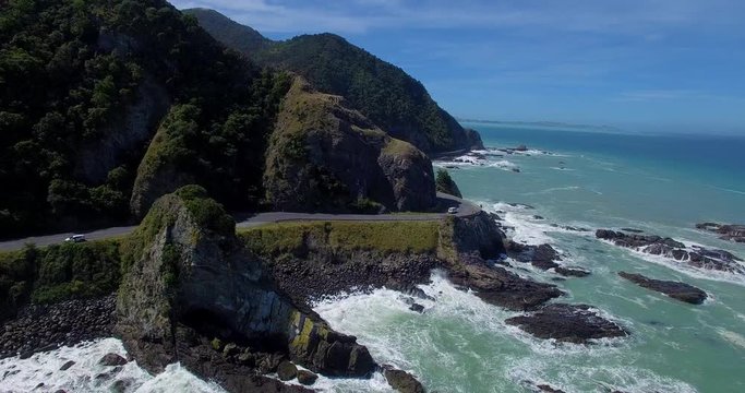 NEW ZEALAND – MARCH 2016 : Aerial shot over the ocean along West Coast Road with road, waves and rocks in view on a sunny day