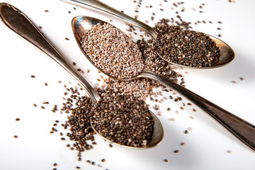 2 kinds of Chia seeds on old vintage silver spoons on white background