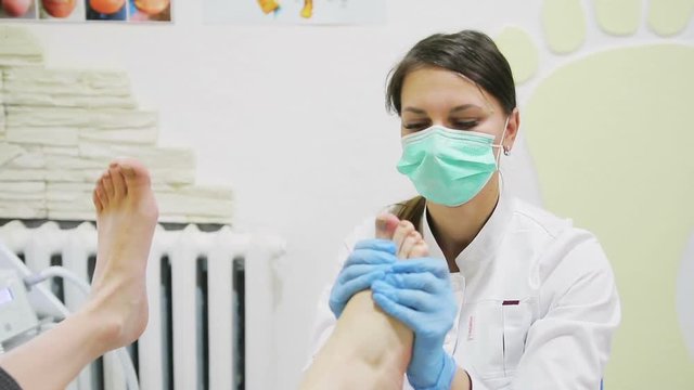 doctor of podiatr makes foot massage to a young girl in clinic