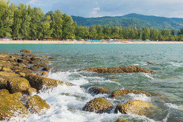A wave of water refreshing a stone in the beach in a sunny day
