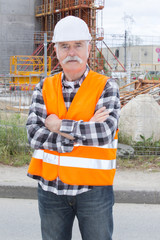 Obraz na płótnie Canvas happy senior construction worker smiling with arms crossed
