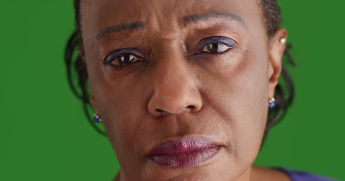 A close-up of a elderly black woman looking off in the distance sadly on green screen. On green screen to be keyed or composited. 
