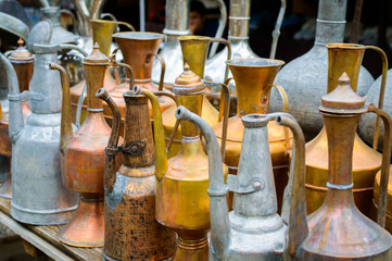 Antique brass jugs and dishes on street market.
